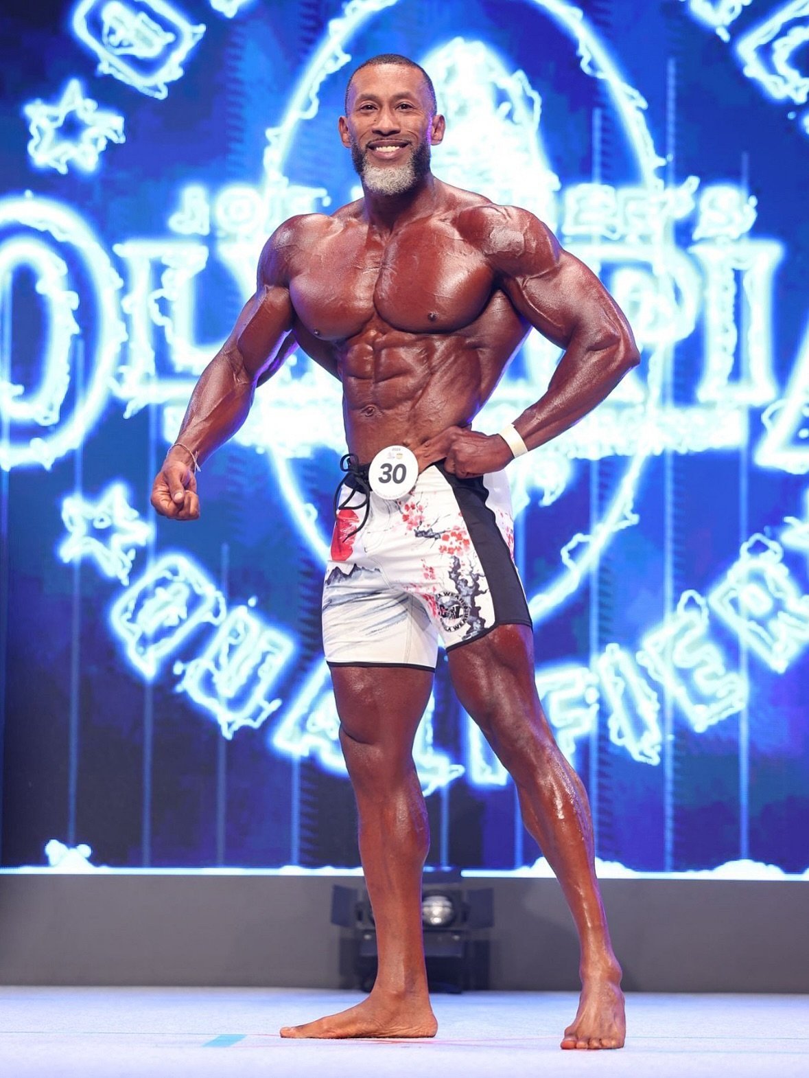 AJ Ellison posing on the Masters Olympia stage in Tokyo, 2025