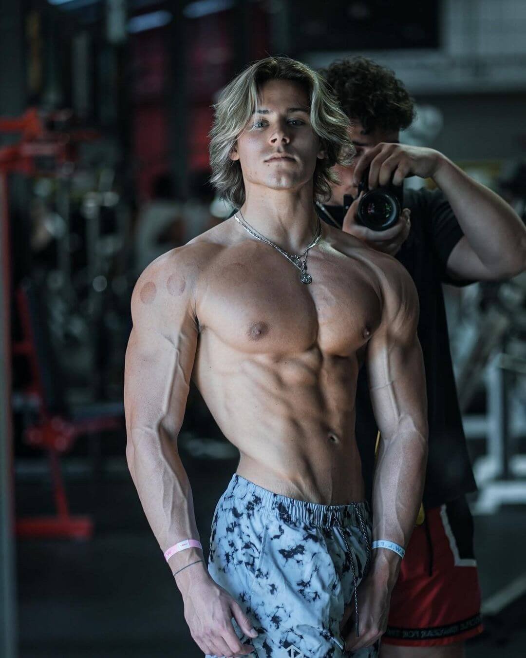 Alex Eubank posing during a gym photo shoot, showing his chest and arm development