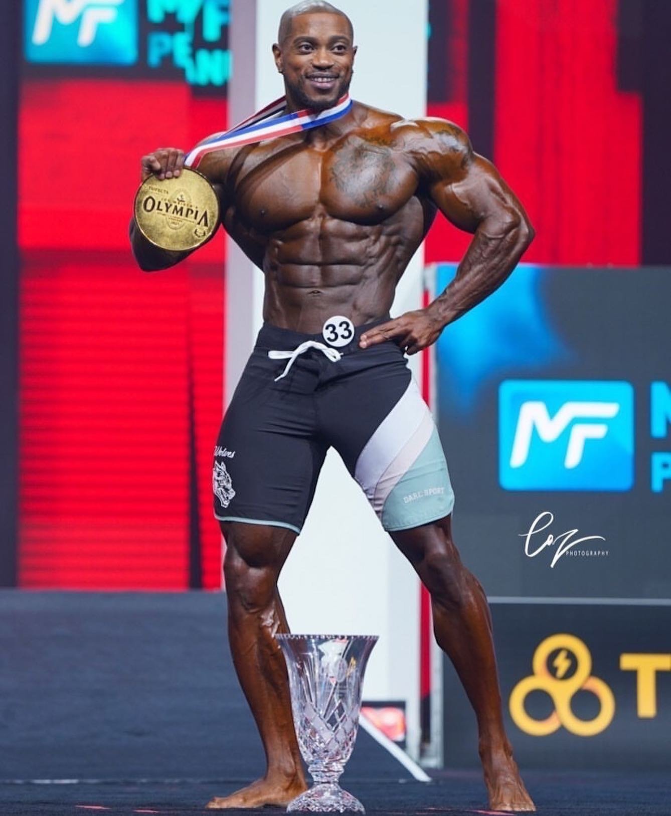 Brandon Hendrickson on the Olympia stage with his medal and trophy