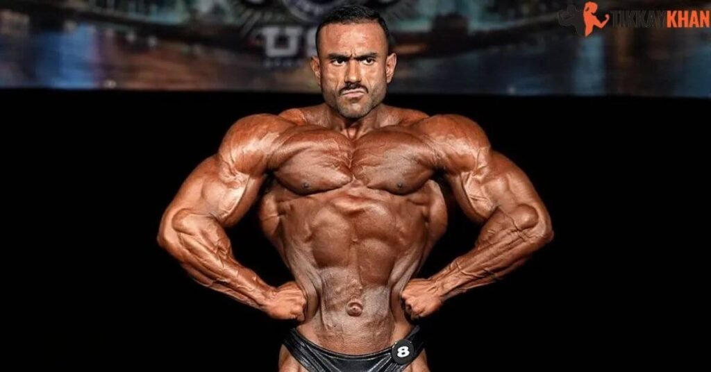 Camilo Diaz on stage, front pose, black posing trunks, number 8