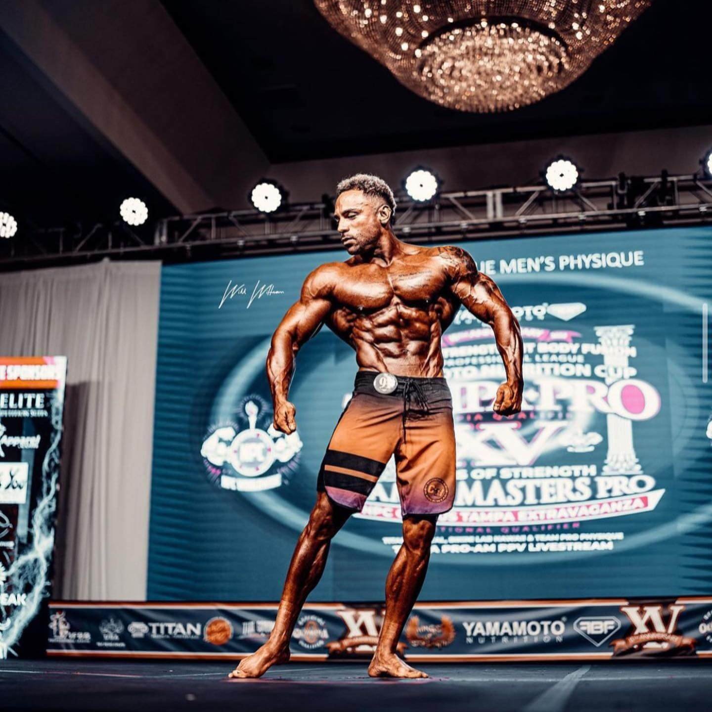 Daniel Ammons on stage in board shorts, Tampa Pro backdrop