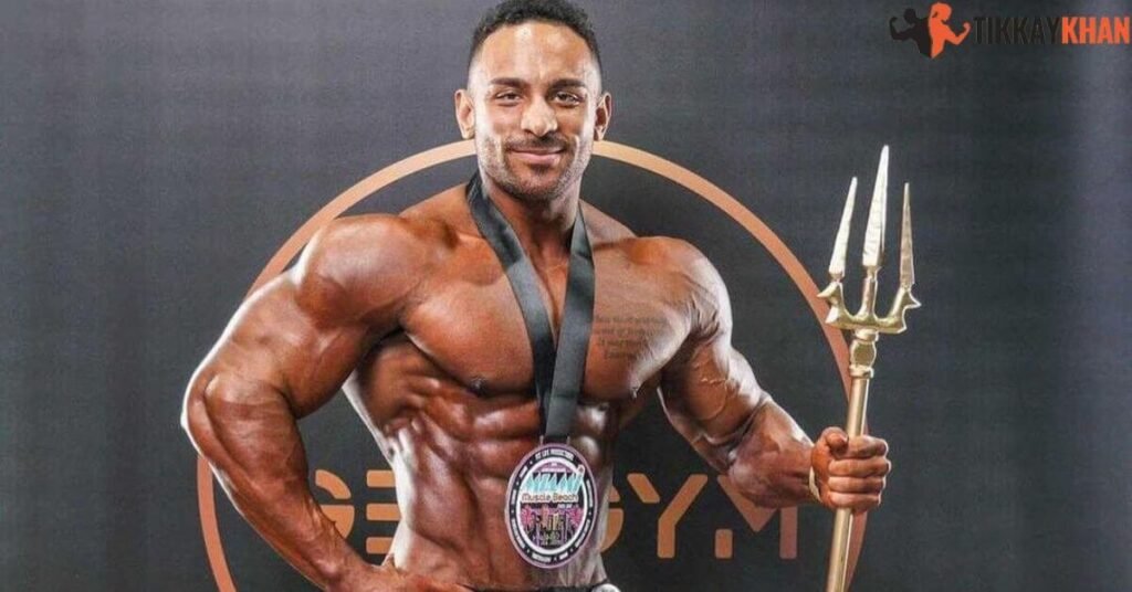 Daniel Ammons front pose holding a Miami Muscle Beach winner's medal and trident trophy