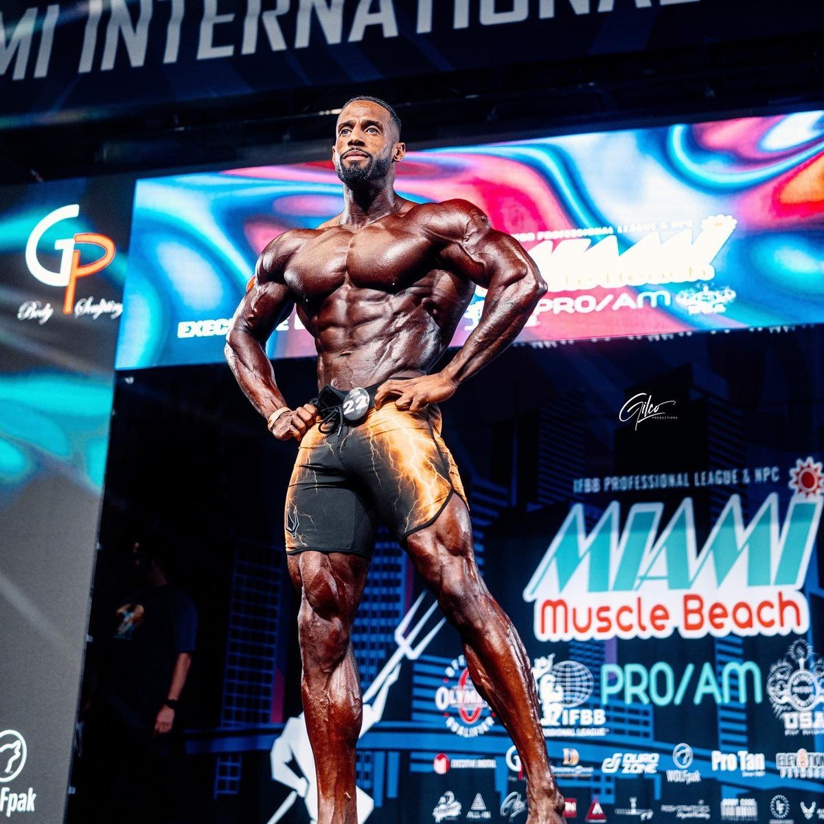Deke Walker on stage at the Miami Muscle Beach Pro wearing competitor number 22 board shorts
