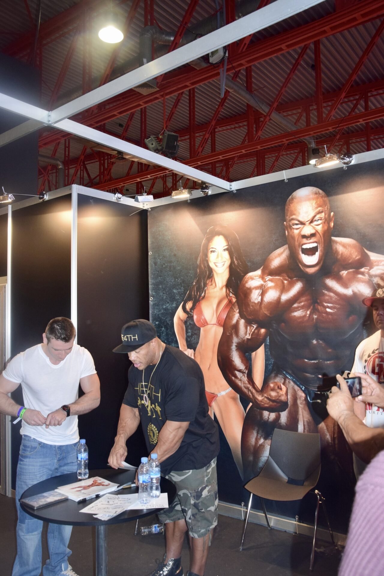 Phil Heath at the Arnold Classic Europe expo in 2014, beside a poster of his most muscular pose