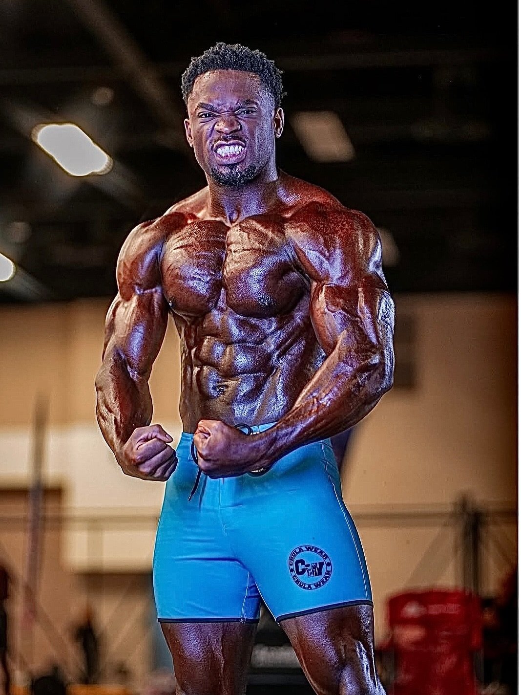 Emanual Hunter posing backstage in teal board shorts