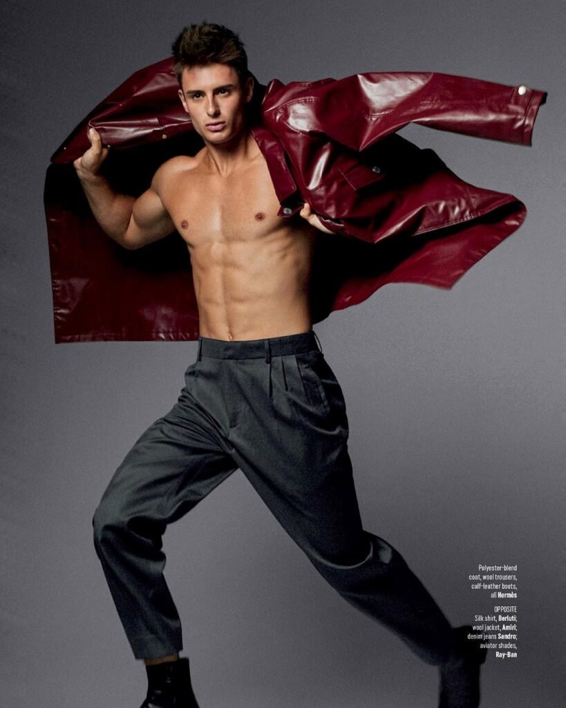 Fabian Arnold in a fashion editorial, opening a red leather coat to reveal his physique