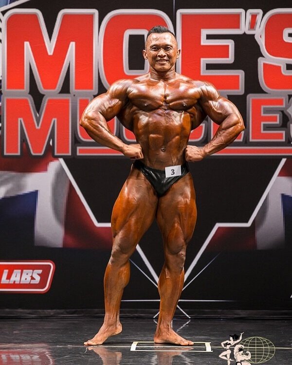 Fanni Fuadi performing a front lat spread on stage at the Moe's Muscles Pro in Auckland