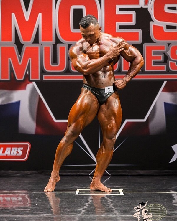 Fanni Fuadi performing a side chest pose on stage at the Moe's Muscles Pro in Auckland