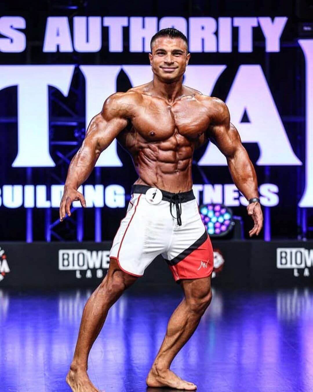 Furkan Er on stage in board shorts, Biowell backdrop