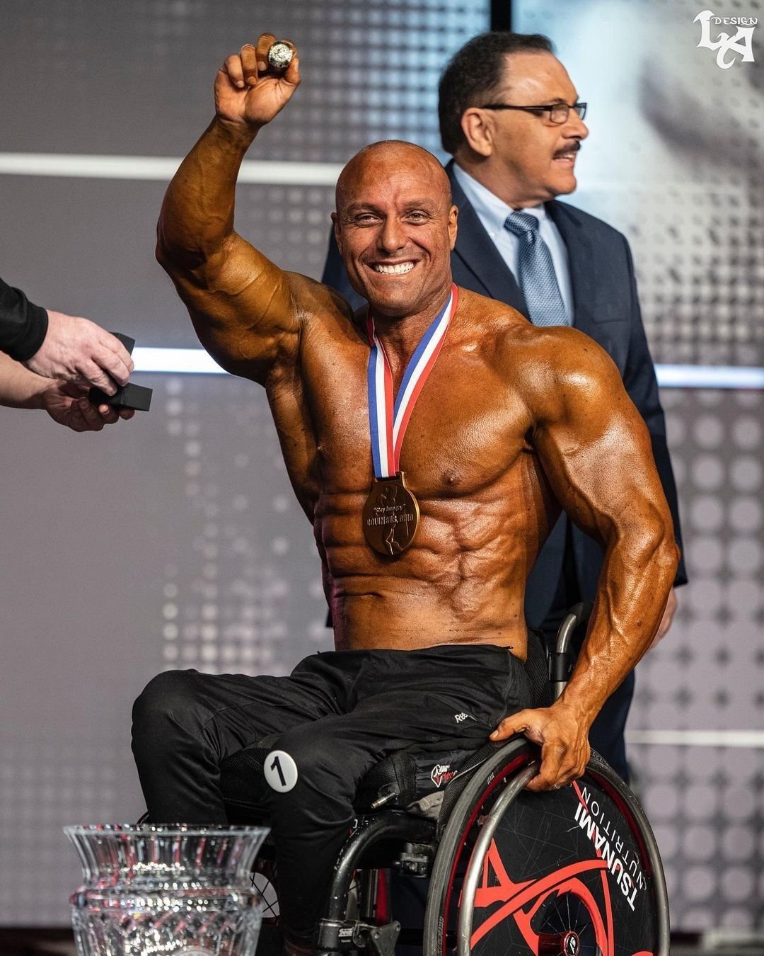 Gabriele Andriulli celebrating with a medal and championship ring in his wheelchair