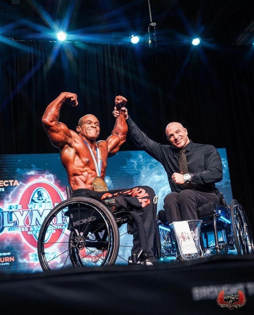 Harold Kelley celebrating with his Olympia medal on stage