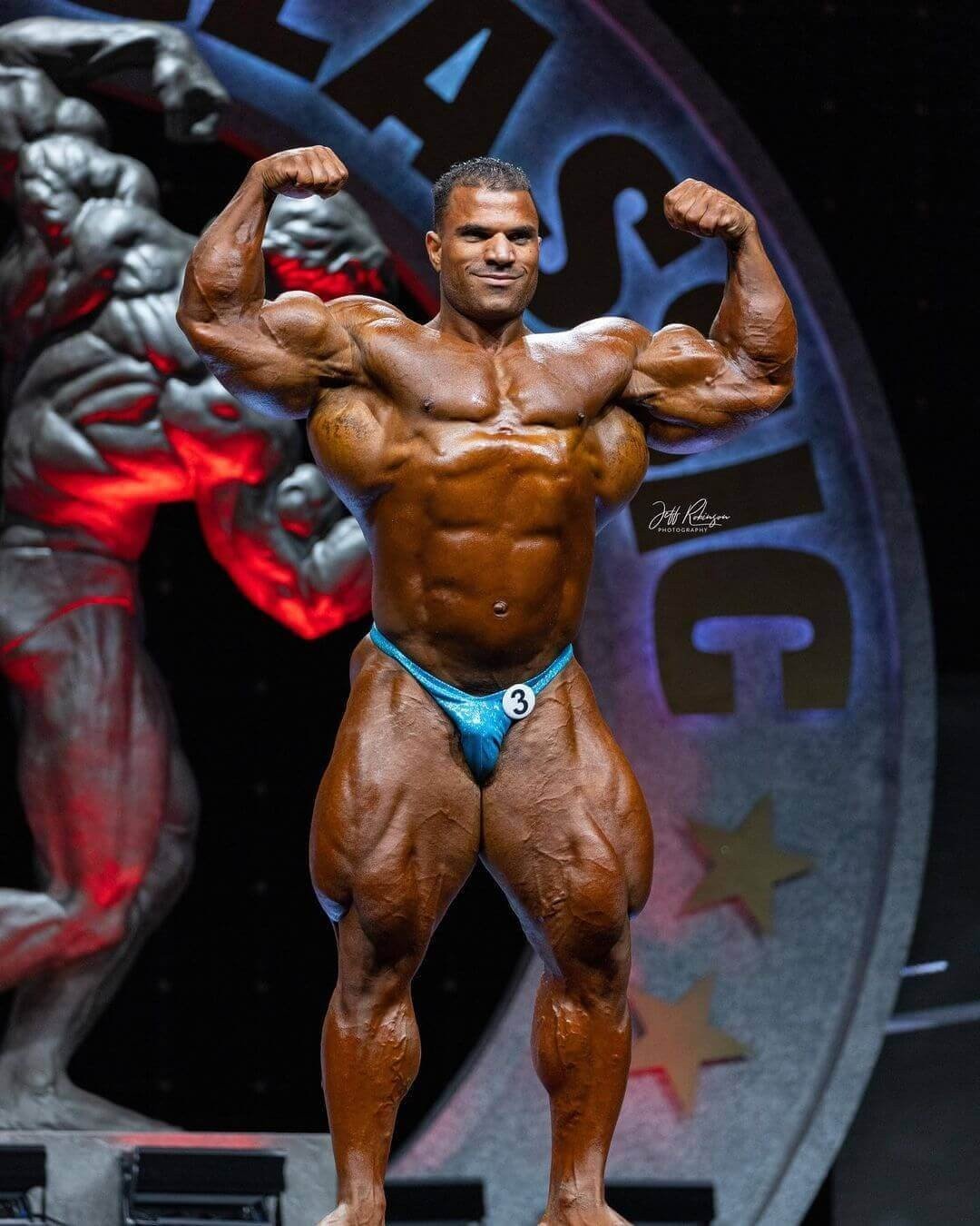 Hassan Mostafa hitting a front double biceps pose on the Arnold Classic stage