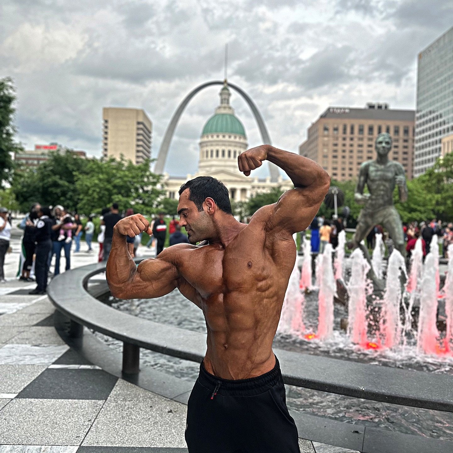 Hossein Karimi flexing outdoors in front of the Gateway Arch in St. Louis