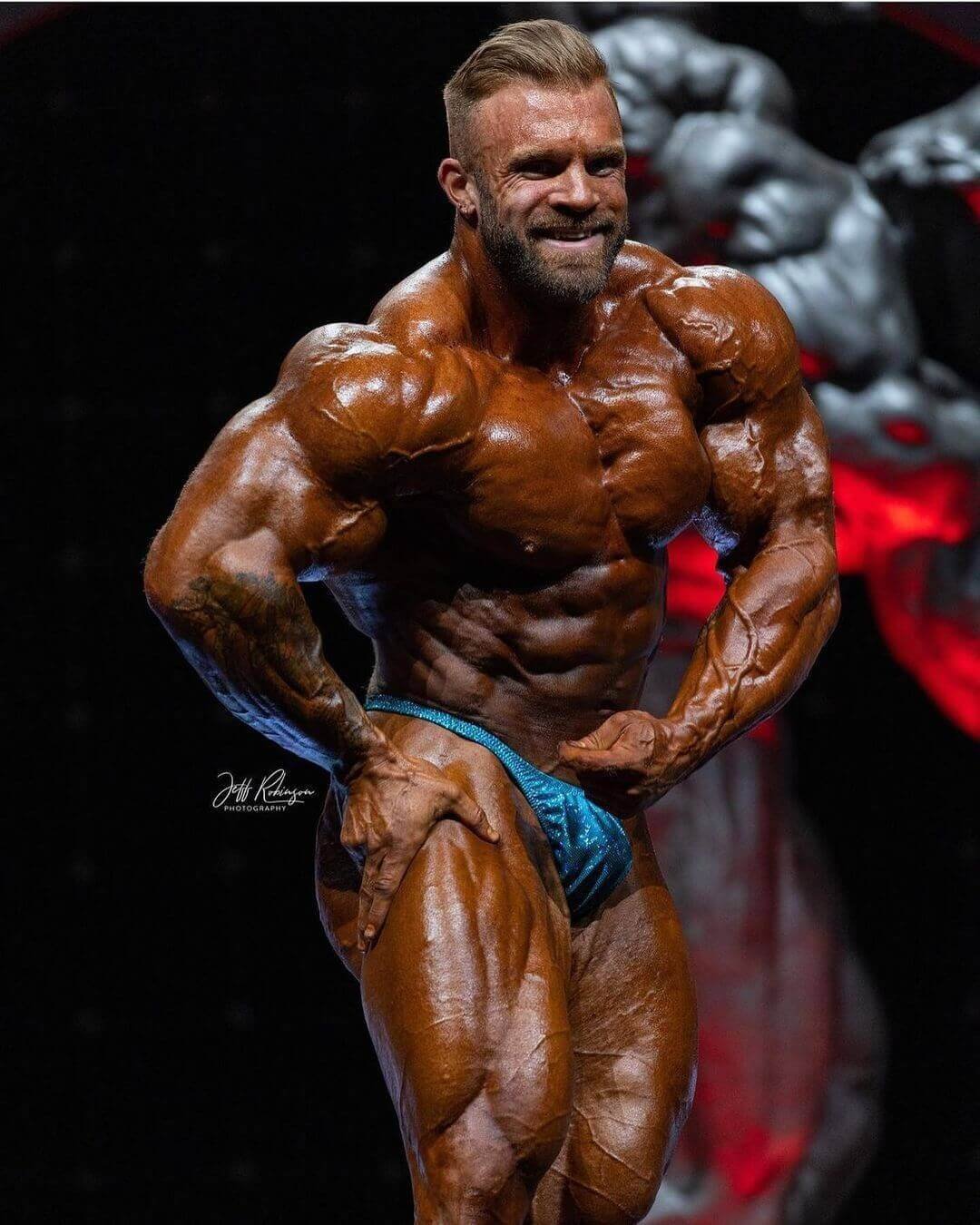 Iain Valliere in a side pose showing his arm and leg development