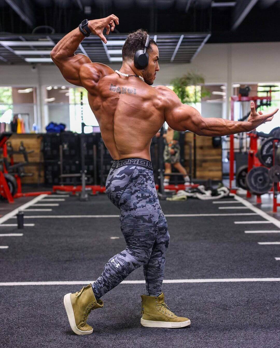 Joshua Manoi from behind in a back pose, showing his back tattoo