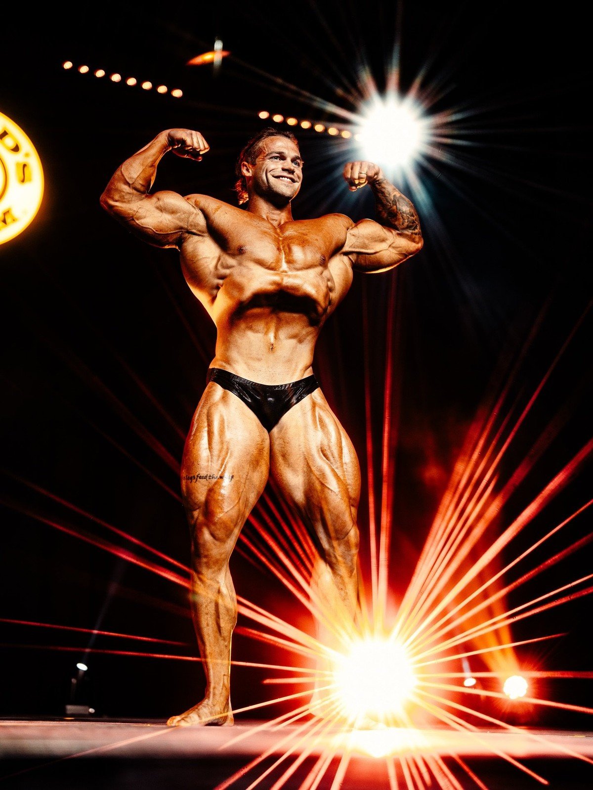 Justin Badurina hitting a front double biceps pose on the Mr. Olympia stage