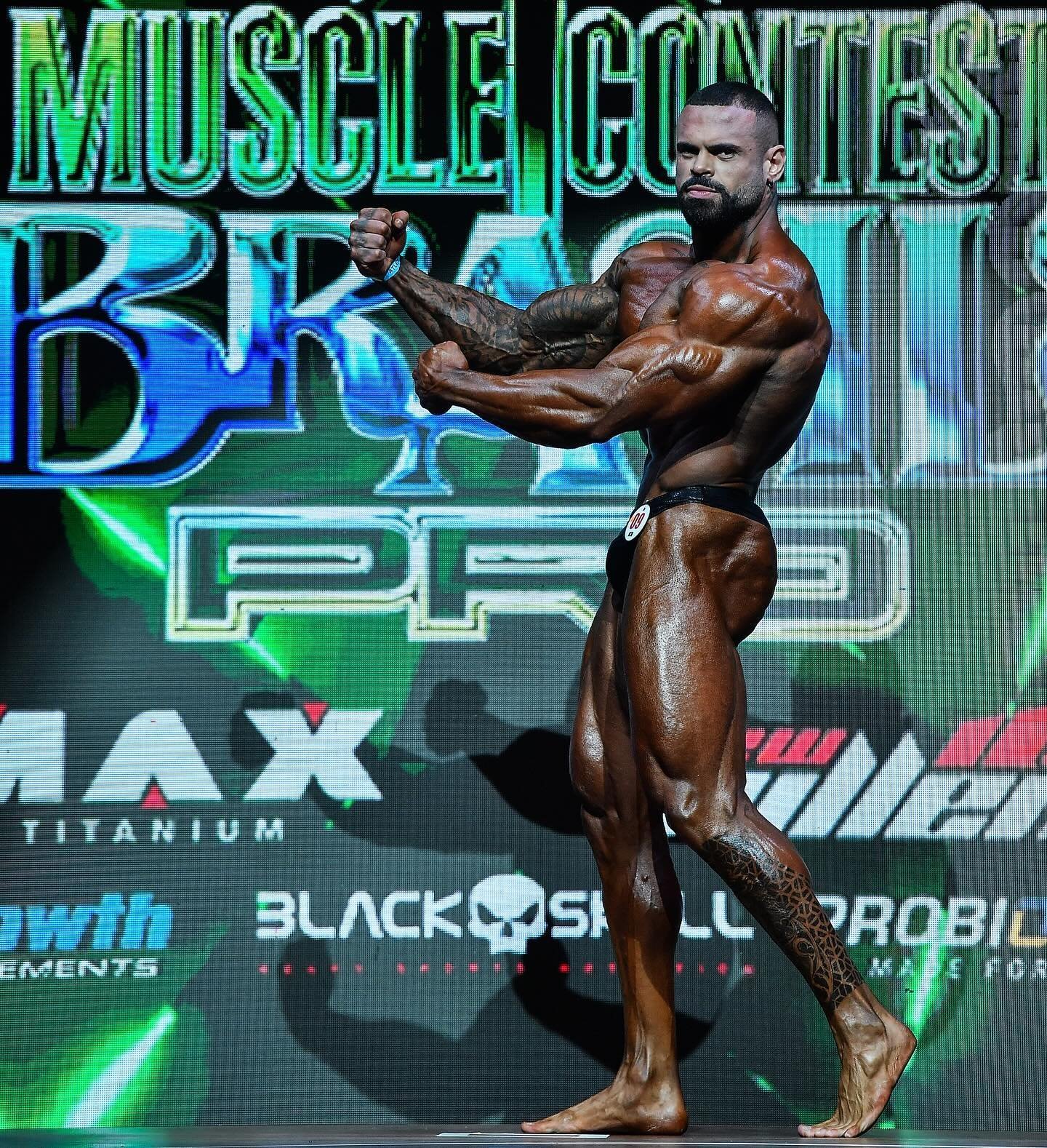 Kenny Moreira hitting a side triceps pose on stage at the Musclecontest Brasil Pro