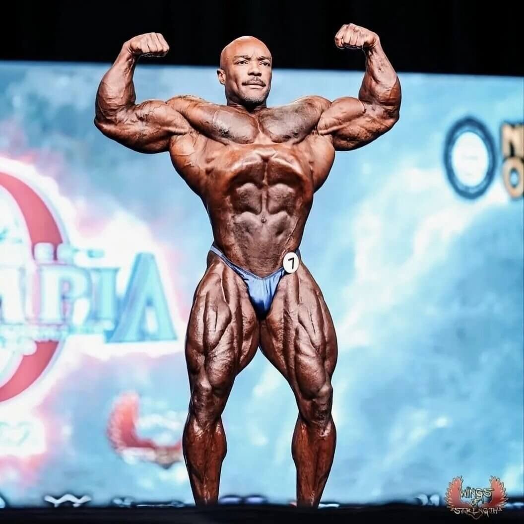 Kerrith Bajjo hitting a front double biceps pose at the Olympia