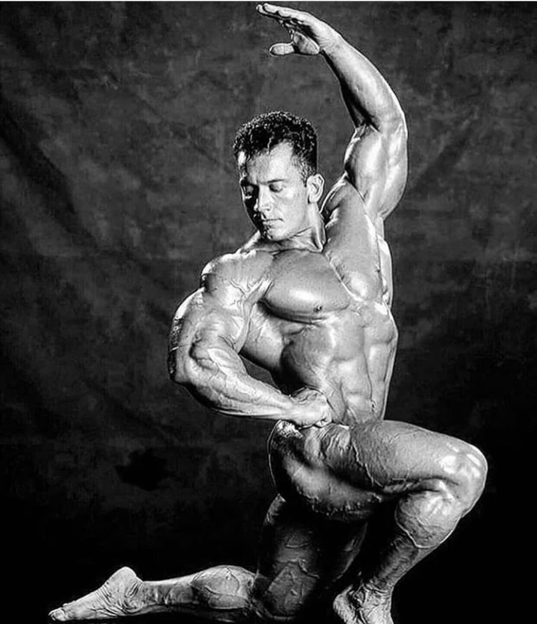 Lee Labrada in a black-and-white artistic posing shot, one arm arched overhead
