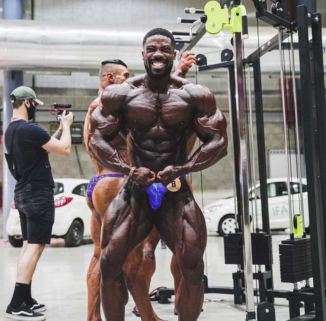 Marc Hector backstage at a bodybuilding contest in posing trunks