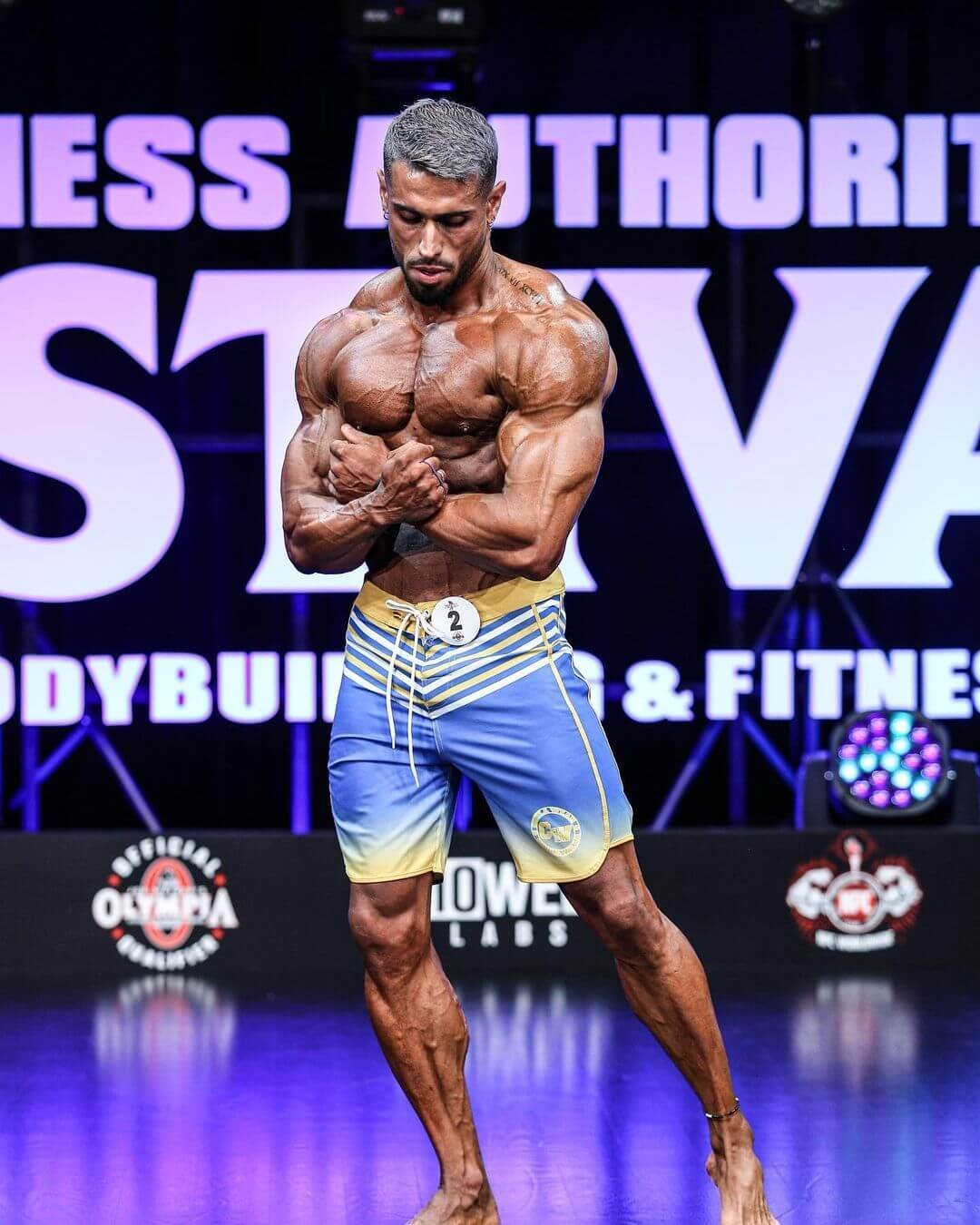 Mauro Fialho on stage in blue and yellow board shorts, mid-pose
