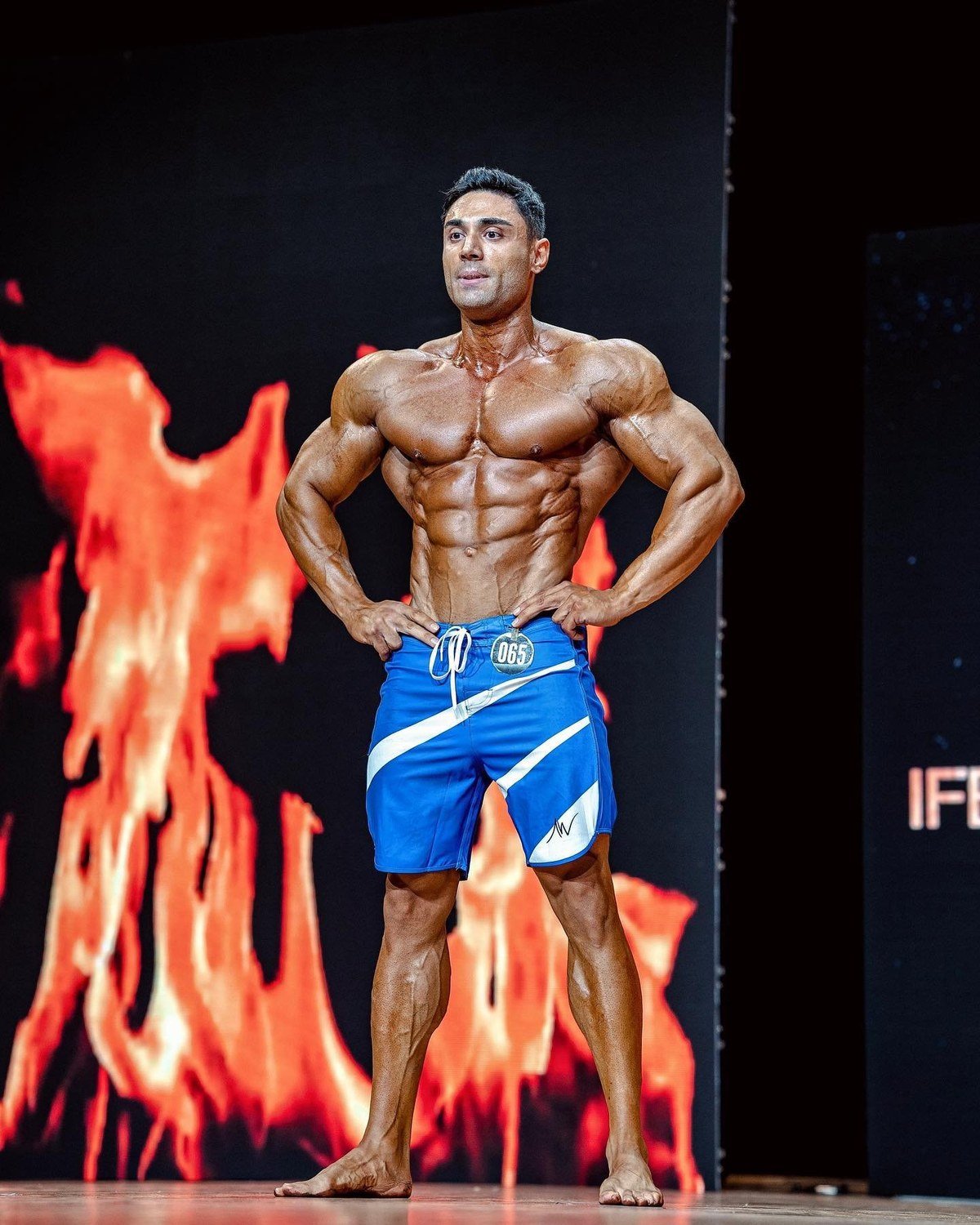 Ozcan Kirant on stage in blue board shorts during pro competition