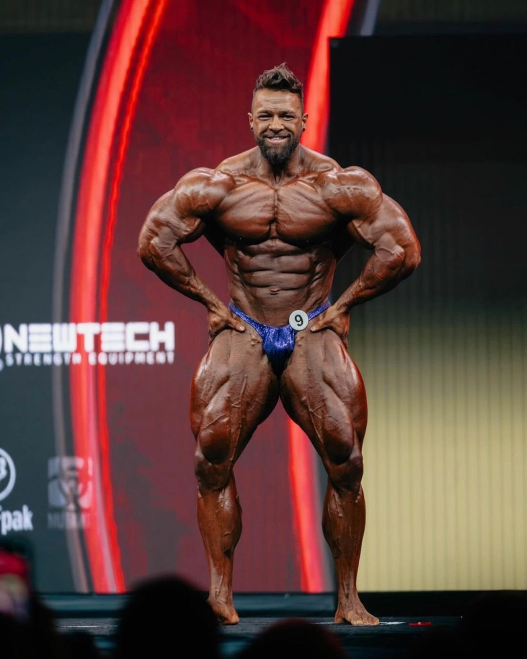 Regan Grimes posing in a front lat spread on stage