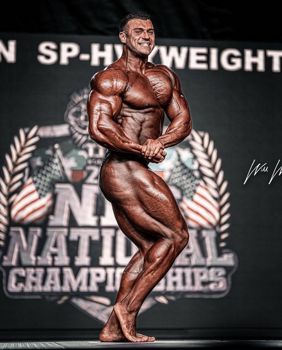 Ryan Crowley hitting a side pose on stage at the NPC National Championships