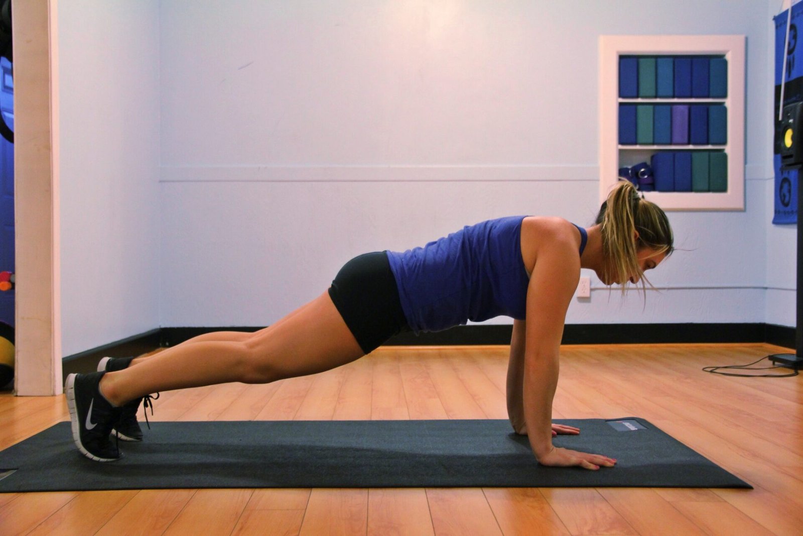 A woman holding a straight-arm plank on a mat indoors