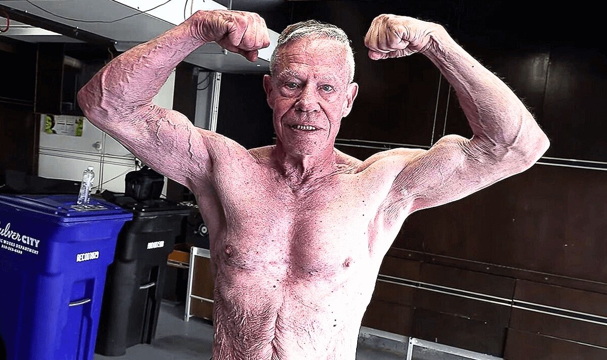 Jim Arrington flexing both arms in a gym