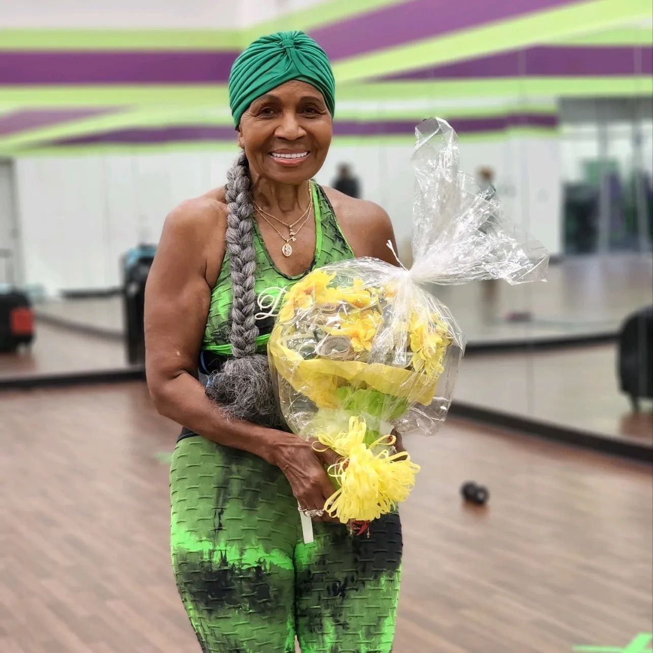 Ernestine Shepherd smiling in green gym wear holding flowers