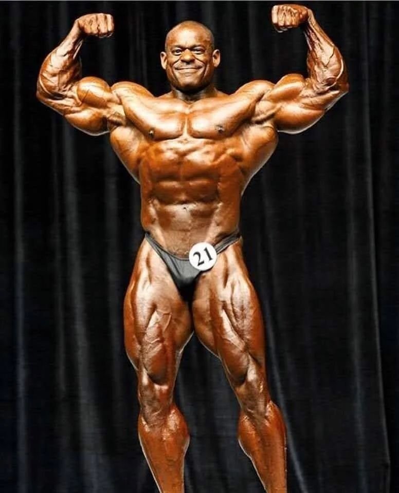 Vince Taylor on stage in a front double biceps pose during his comeback era