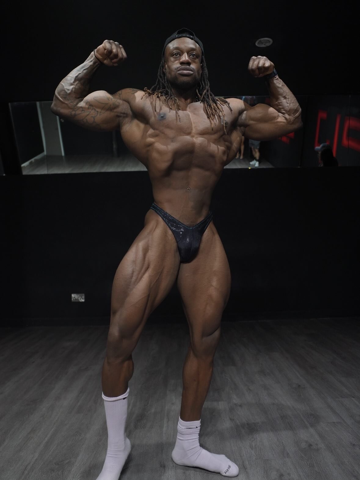 Yemi Adefioye hitting a front double biceps pose in the gym